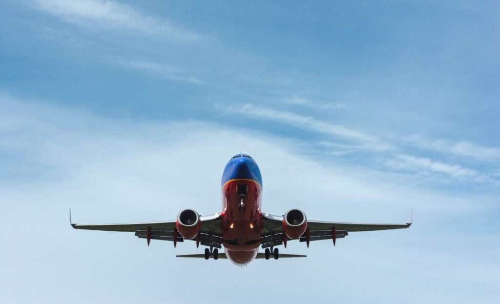 Airplane flying against a clear blue sky, representing direct international flights to Belize