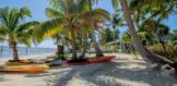 Beachfront view on Ambergris Caye with kayaks resting in the sand, offering direct access to the Caribbean Sea and stunning tropical surroundings