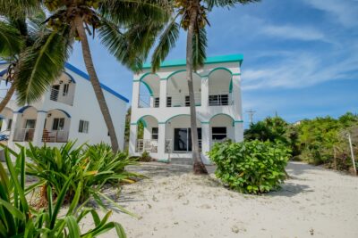 Front view of a beautiful 2-bedroom, 2-bath home for sale in North Ambergris Caye, featuring tropical landscaping and a spacious exterior