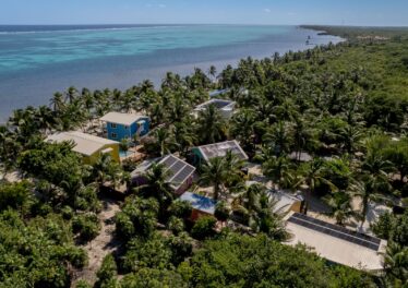 Aerial view of Casitas Belice beachfront resort on Ambergris Caye, showcasing six rental units, swimming pool, private pier, and lush tropical landscaping