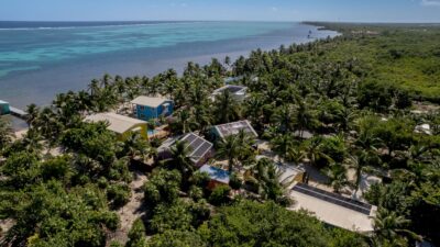 Aerial view of Casitas Belice beachfront resort on Ambergris Caye, showcasing six rental units, swimming pool, private pier, and lush tropical landscaping