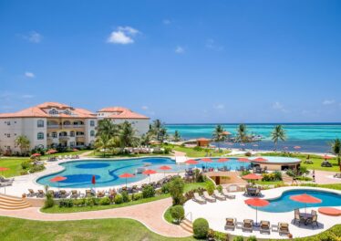 Panoramic view of Grand Caribe Resort in Ambergris Caye, Belize, featuring lush tropical landscaping, beachfront pools, and stunning Caribbean ocean views