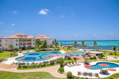 Panoramic view of Grand Caribe Resort in Ambergris Caye, Belize, featuring lush tropical landscaping, beachfront pools, and stunning Caribbean ocean views