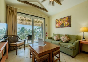 View from living room through glass doors to balcony, showcasing stunning Caribbean Sea views from the oceanfront condo in San Pedro, Ambergris Caye