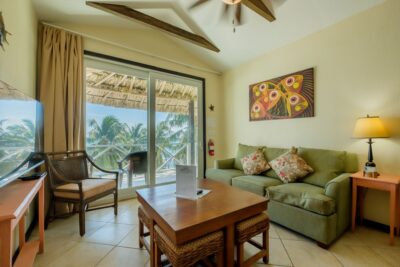 View from living room through glass doors to balcony, showcasing stunning Caribbean Sea views from the oceanfront condo in San Pedro, Ambergris Caye