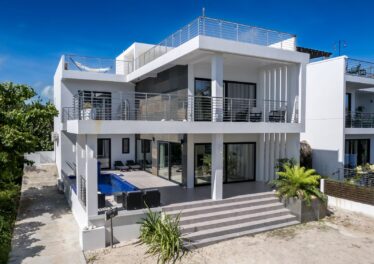 Front view of Everblue Villa, a luxurious beachfront home in Ambergris Caye, Belize, featuring modern architecture and spacious outdoor areas